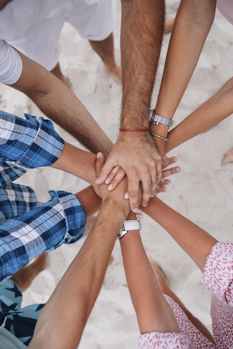 People joining hands together,group of friends keeping hands together.Teamwork concept. On the sandy beach.